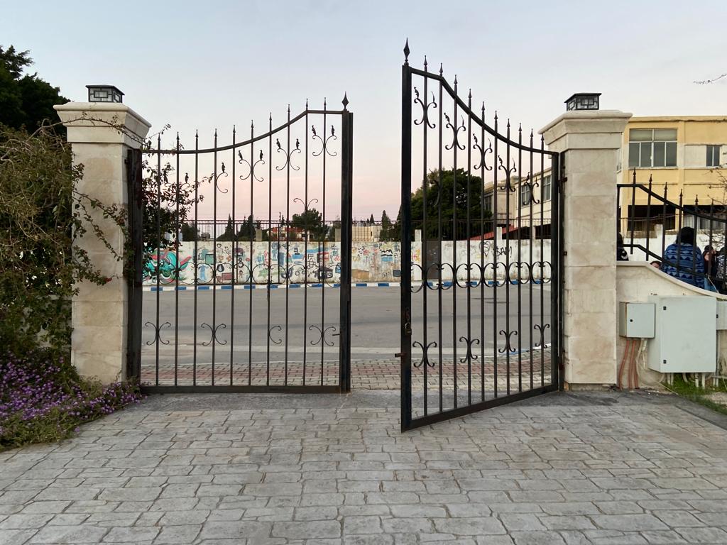 Large double iron gate with one side opening on to the road