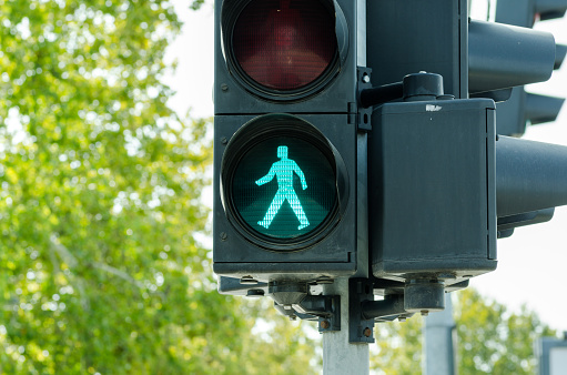 A British traffic light with the pedestrian controls pictured. The green man is lit.